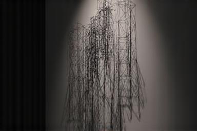 Minimalist shadow art sculpture against a dark textured wall